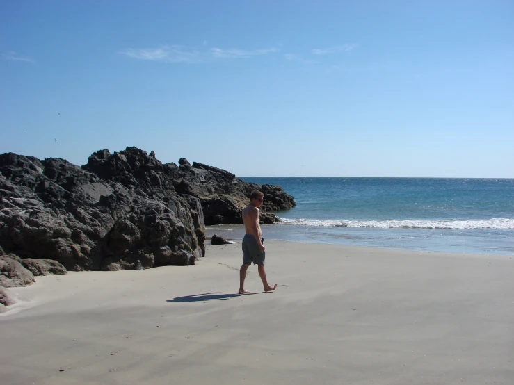 a person stands on the beach as a wave breaks in