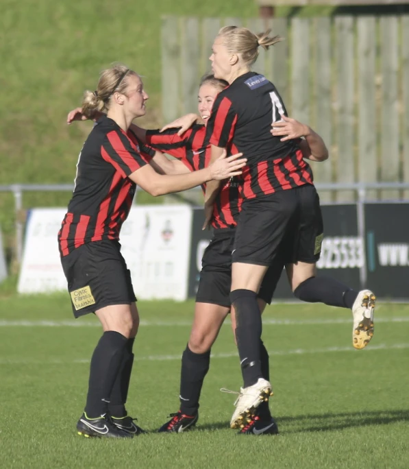 a couple of girls are celeting a goal on a field