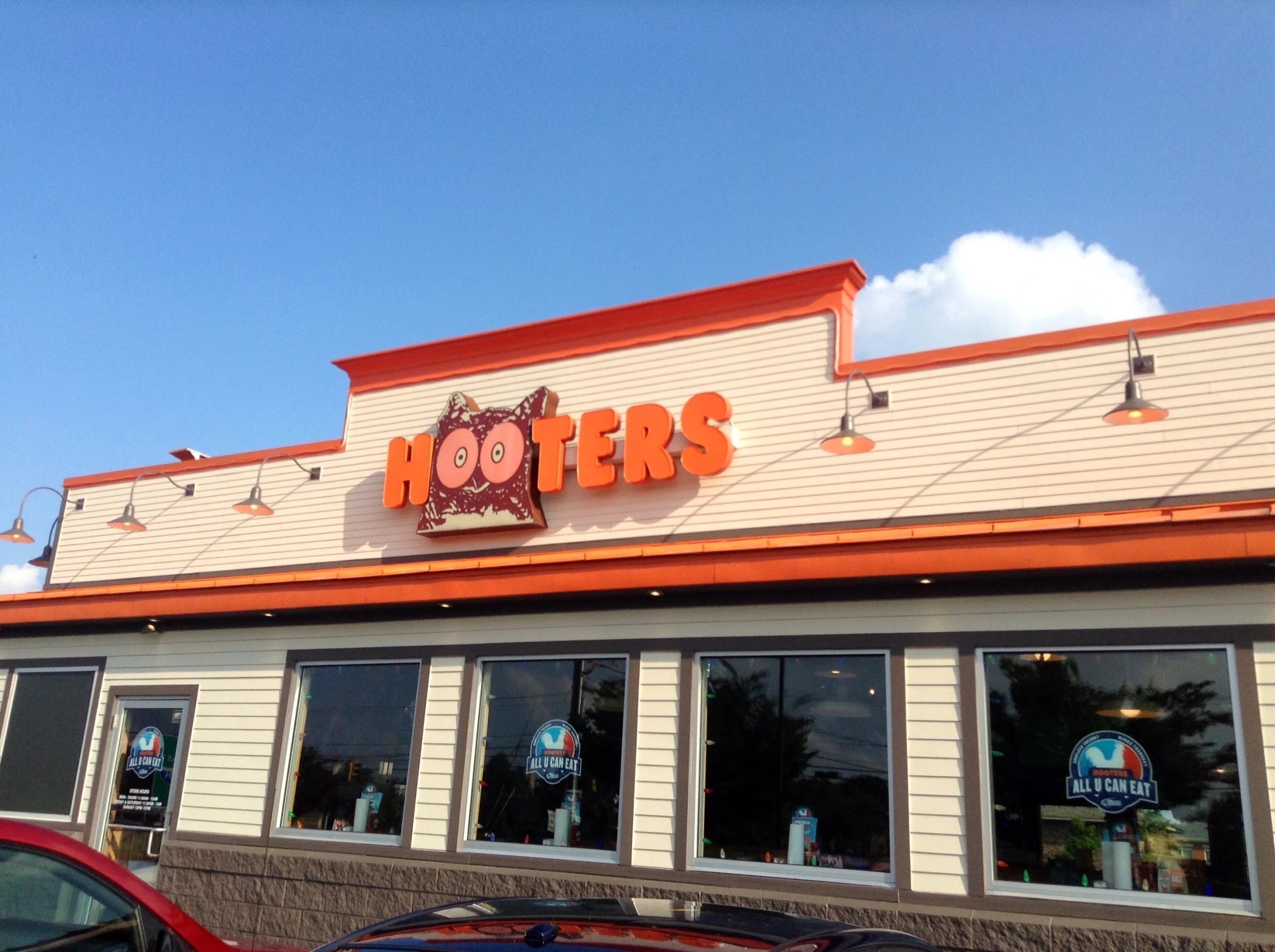 the exterior of a restaurant with many chairs and cars parked outside