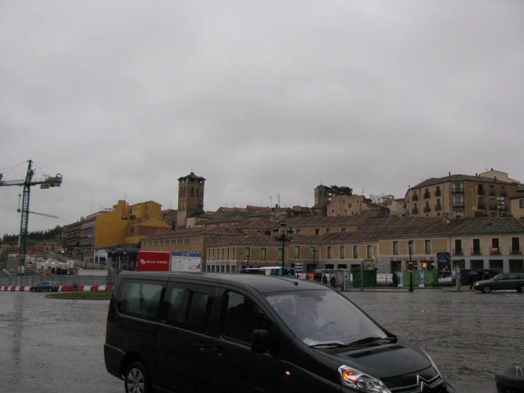 a black mini van on wet pavement in a town