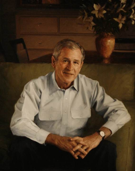 a man in a shirt sits on the couch in front of a potted plant