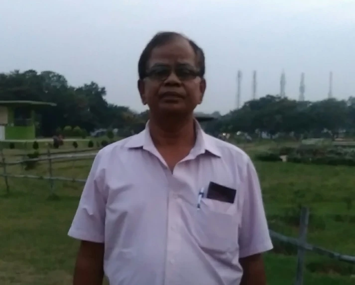 an old man with a pink shirt stands in a green field