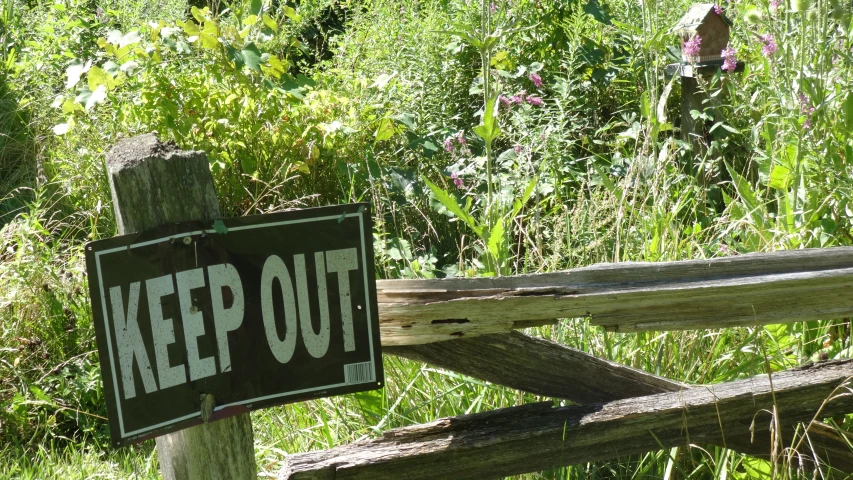 a keep out sign is posted on an old fence