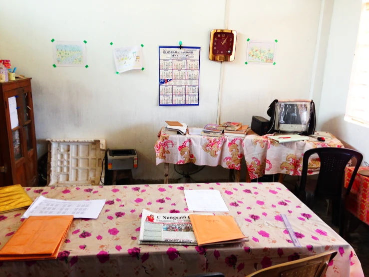 a dining room table and chairs with different pieces of paper strewn all over it