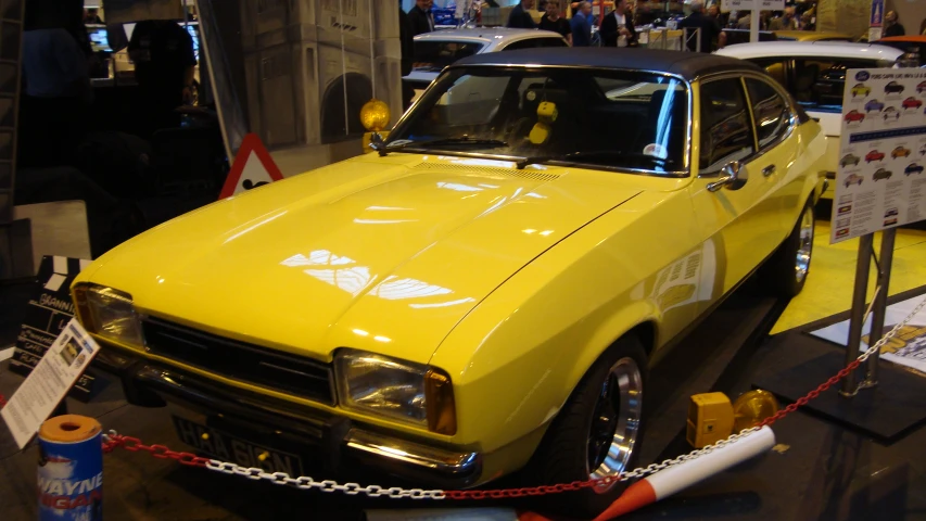 yellow car parked in museum with other vehicles