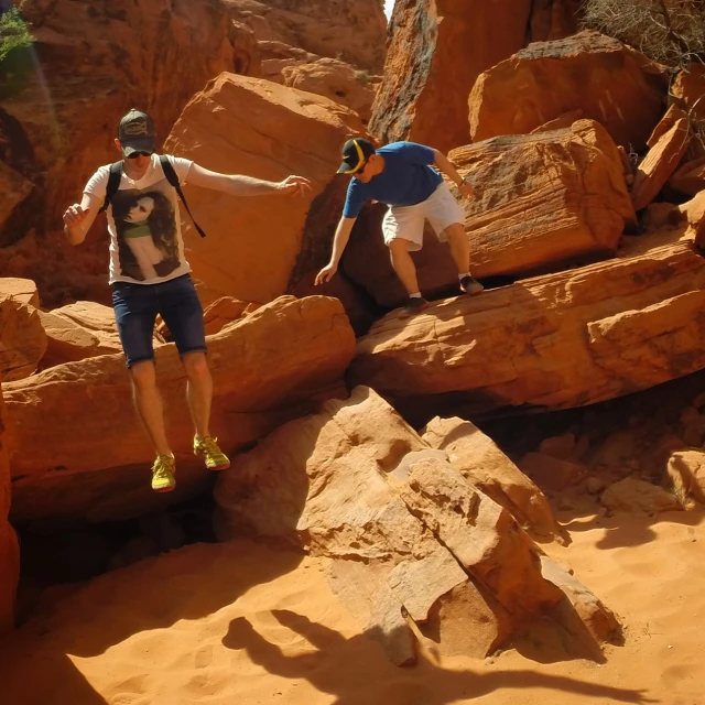 two men climbing around boulders in the desert