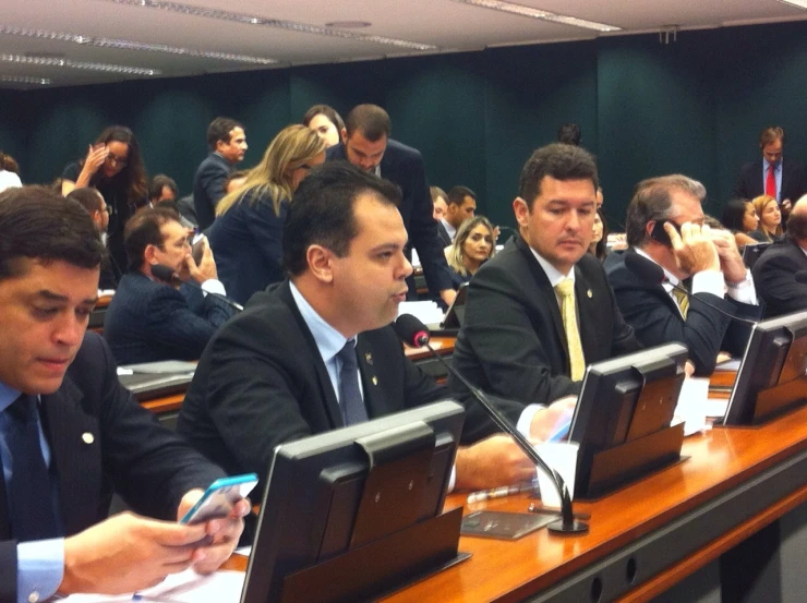 several people sitting at desks with computers and papers