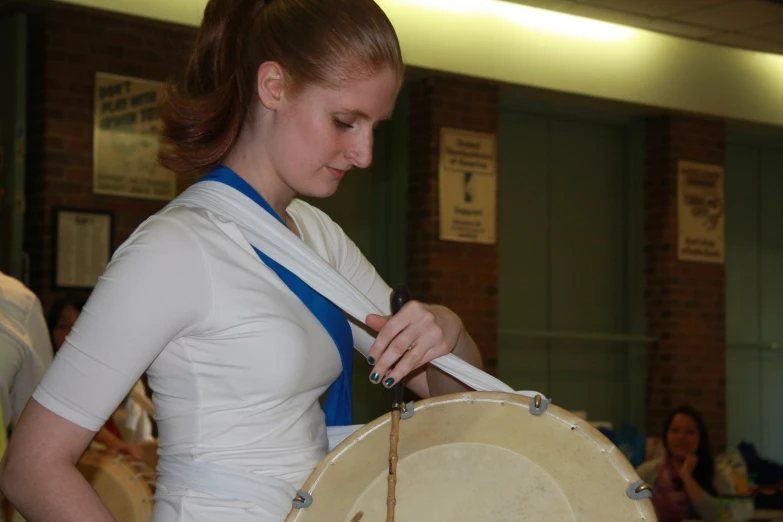 a woman holds a drum in one hand