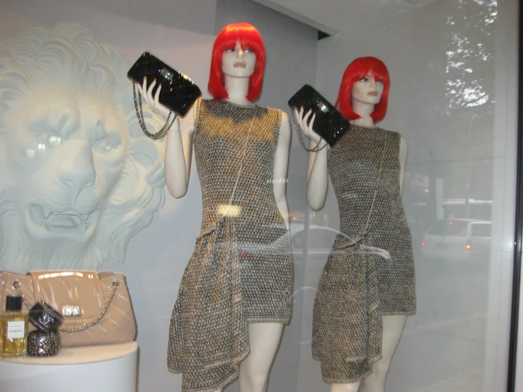 three mannequins dressed in dresses with matching purses on display