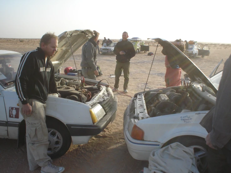 a group of people around parked cars in the desert