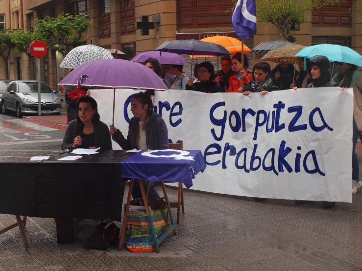 a group of people sit under umbrellas on the street