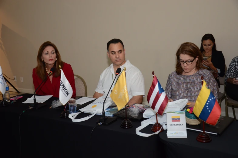 a group of people sitting around tables in front of microphones