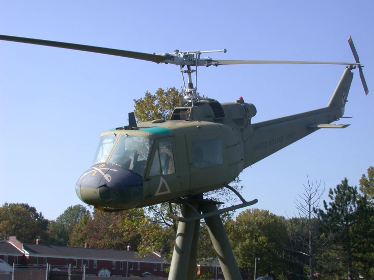 a green helicopter with propellers sitting on top of a cement slab