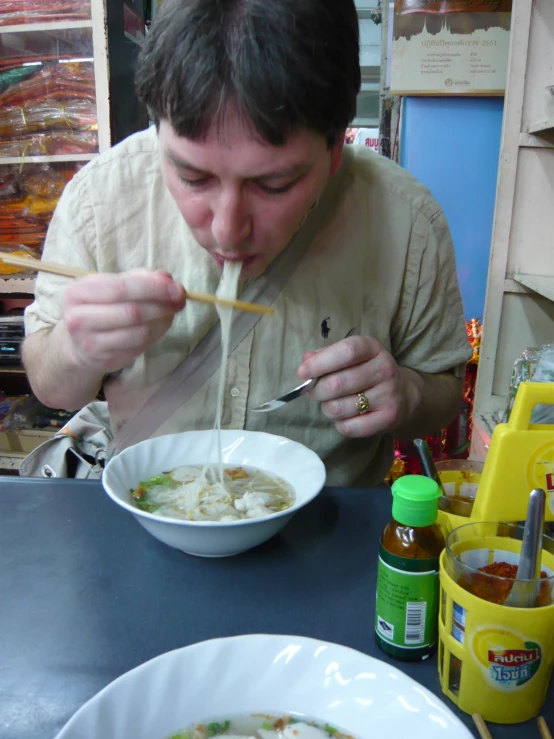 a man is eating soup from a white bowl