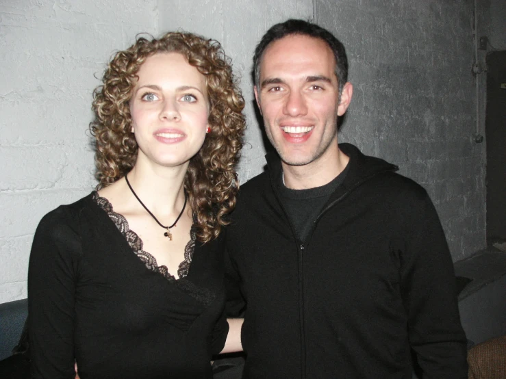 two people posing for a picture in front of a brick wall