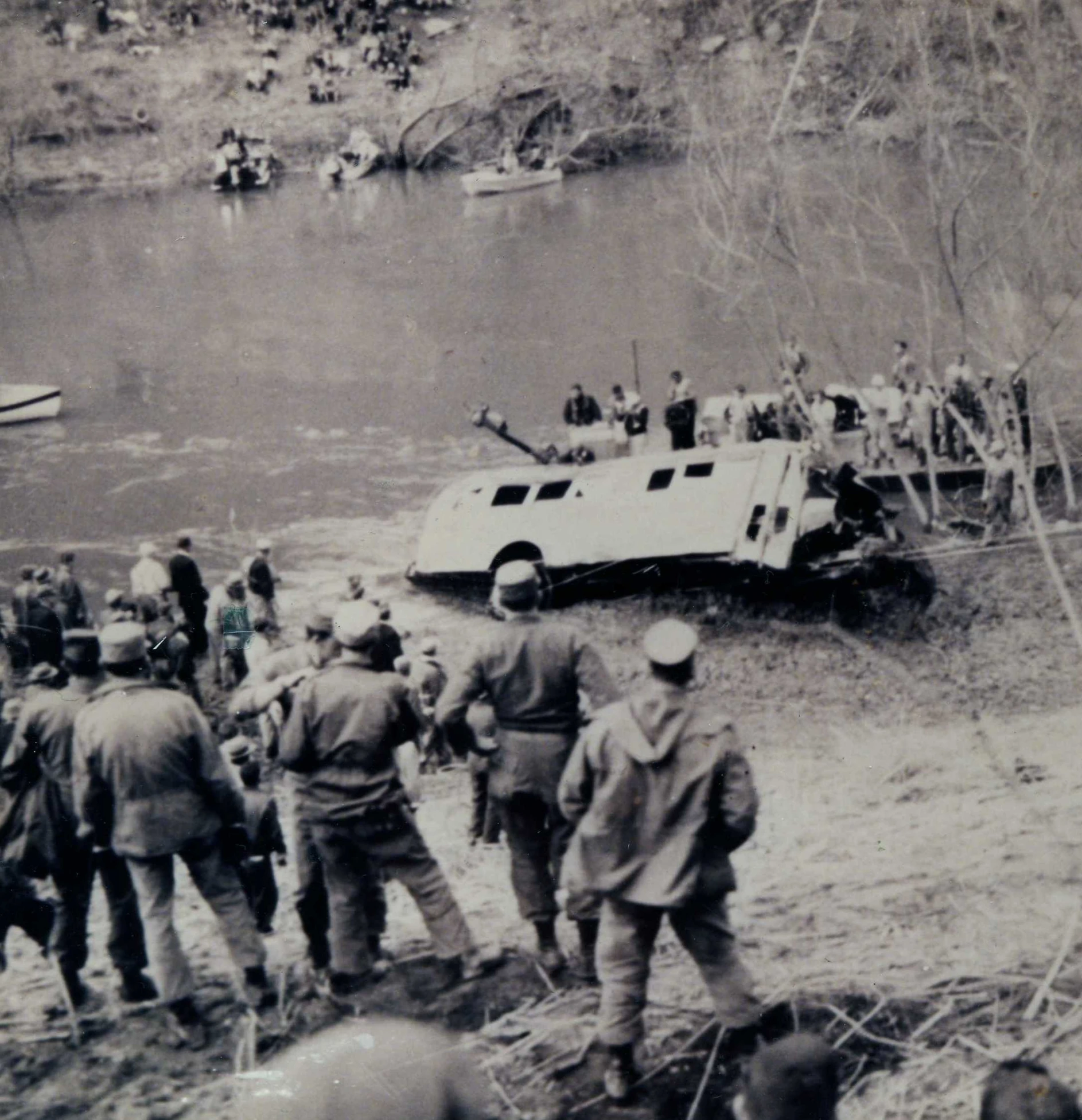 military men are standing near an overturned jeep and boat