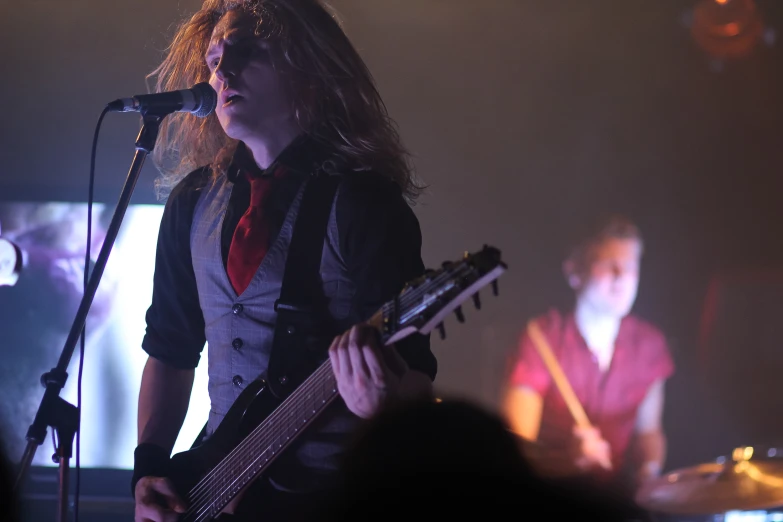 a male in a black jacket playing guitar and singing