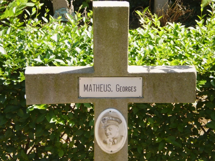 a cross is sitting in the ground with a plaque