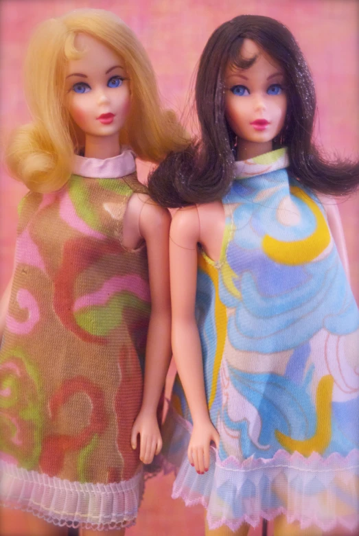 two small dolls, one wearing a colorful dress and the other a green and pink flower