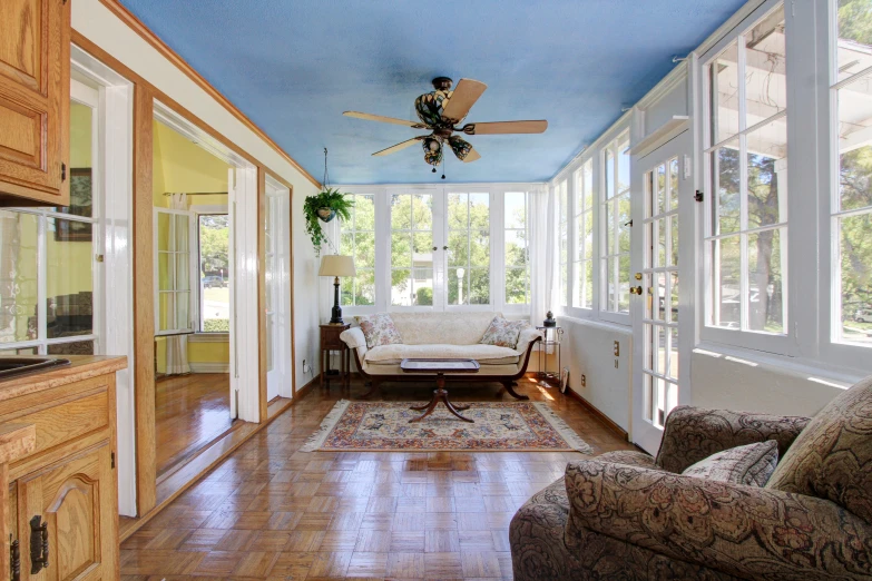 a sunlit sun room with glass walls, wooden floors and ceilings