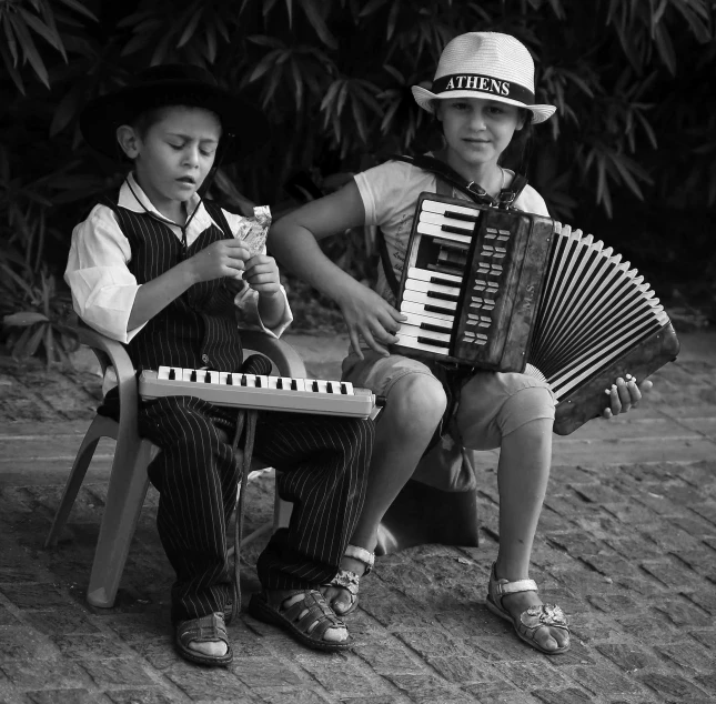 two children sitting on a bench with an accordion