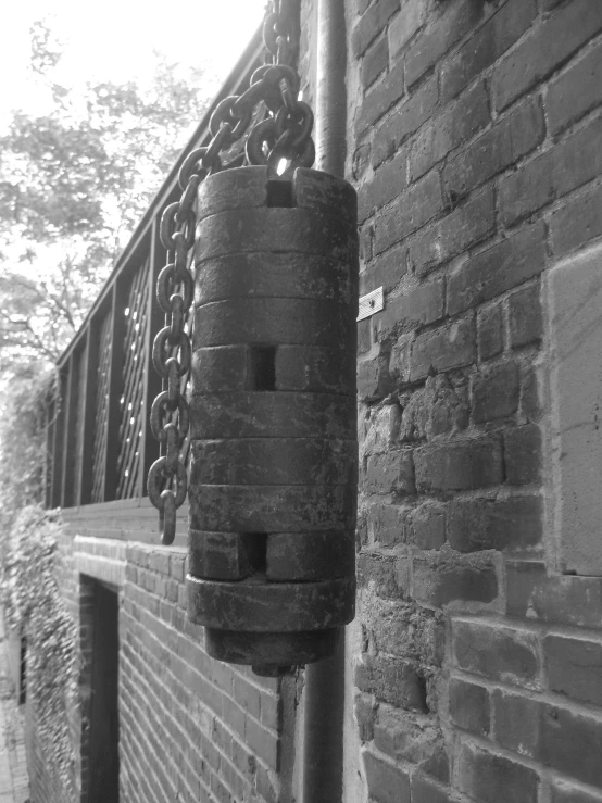 a black and white pograph of an old chain on a brick wall