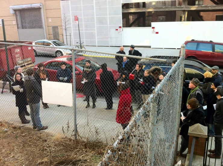 a group of people stand in front of a fence