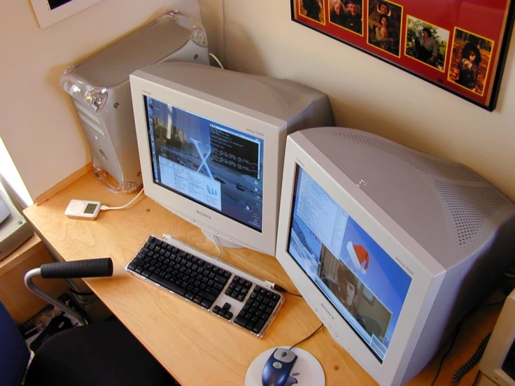 two computers sitting on top of a wooden desk