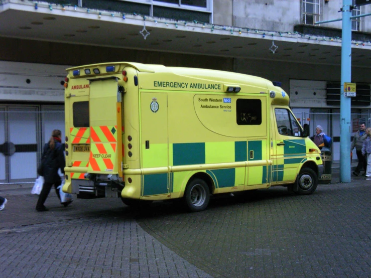 an ambulance parked in a parking lot near some people