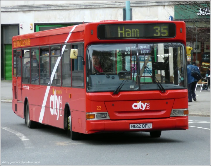 a red city bus drives down the street