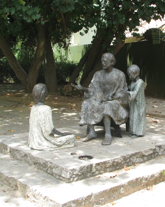 a statue in a park showing three people