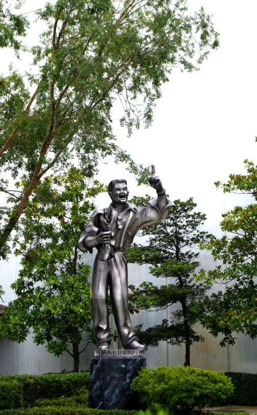 a silver statue in front of a tree