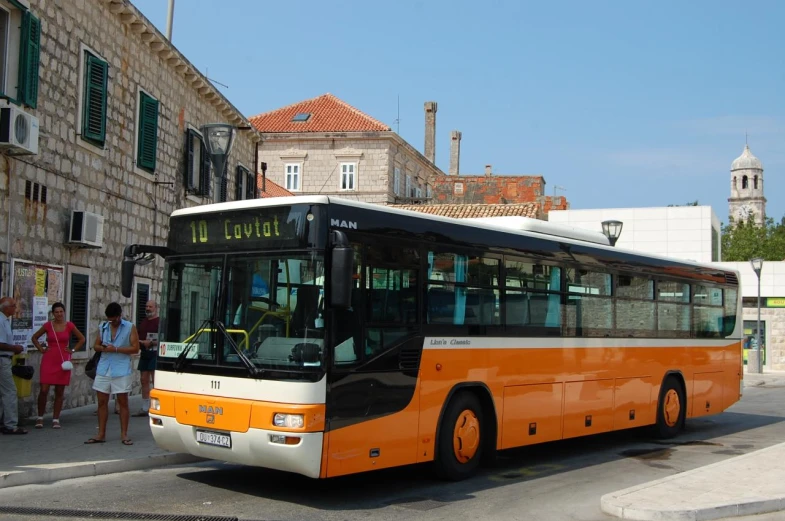 the people are standing in front of a large bus