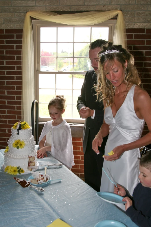 there are people standing around a cake at this wedding