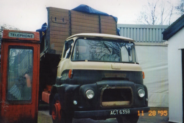 an old truck parked next to a red telephone booth