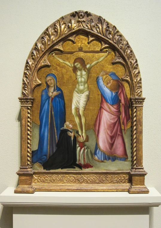 a golden statue with a painting of christ on the cross and two other religious figures behind it