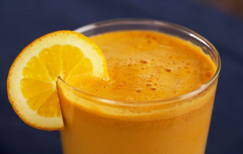 a glass filled with a liquid next to a sliced orange