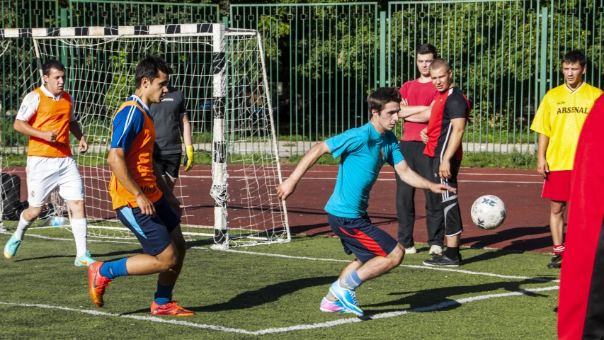 men playing soccer at a school field with the goal being blocked