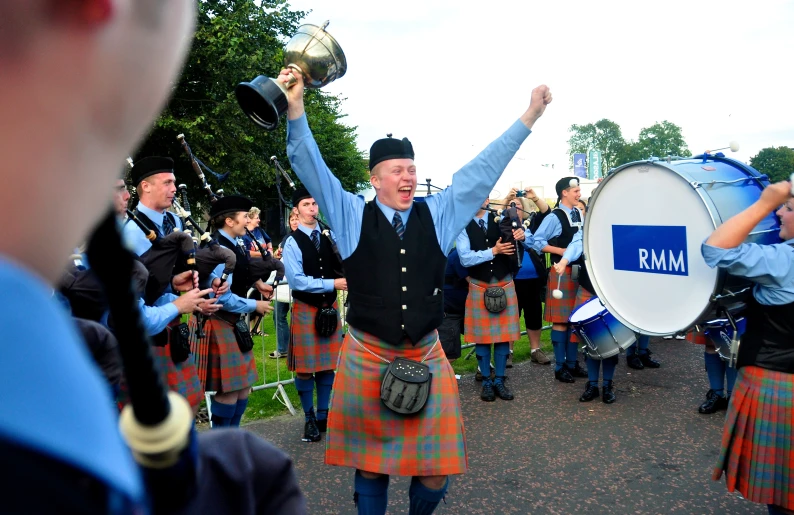 a marching band performs with the person in a kilt