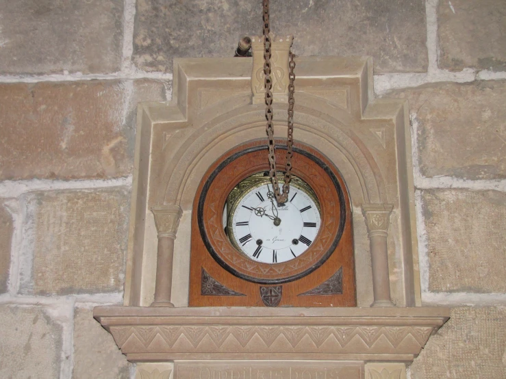 a clock mounted to a wall with a chains around it