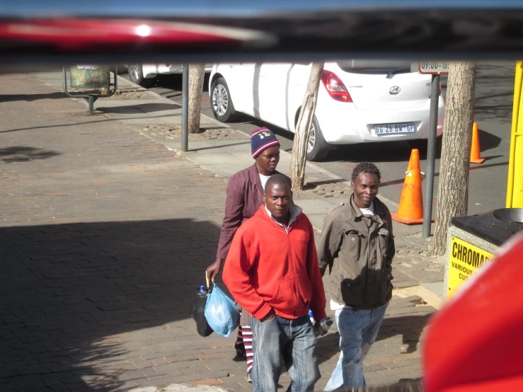 three men walking down the street while holding bags