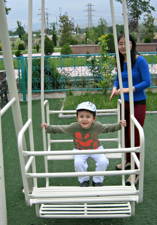 an infant boy playing on the swing with his mother