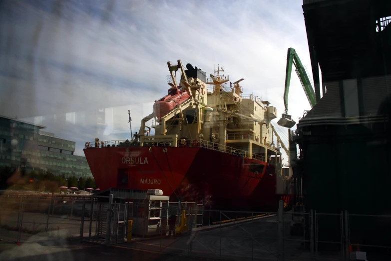 large red boat docked at dock in shipyard