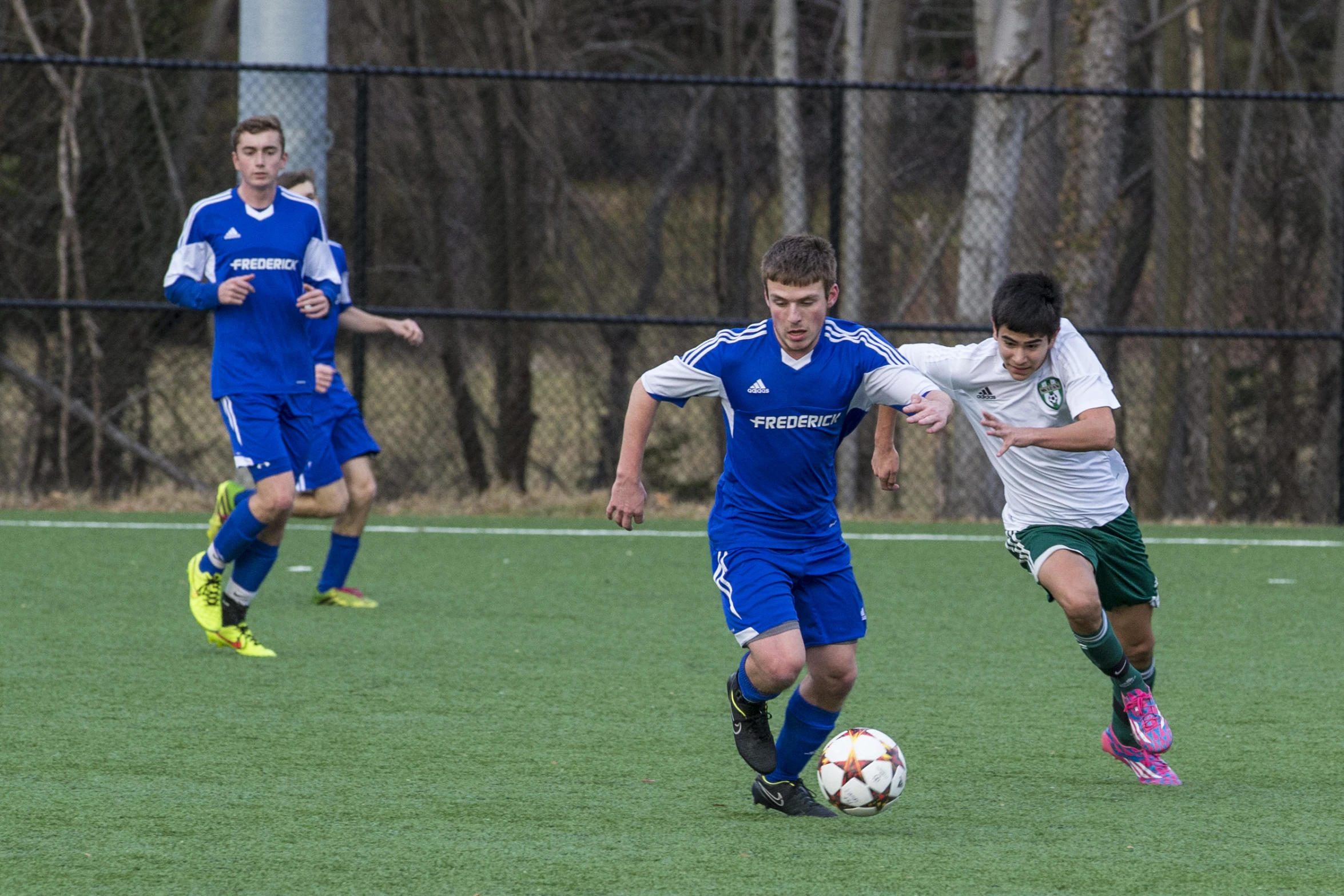 two teams playing soccer and one has the ball