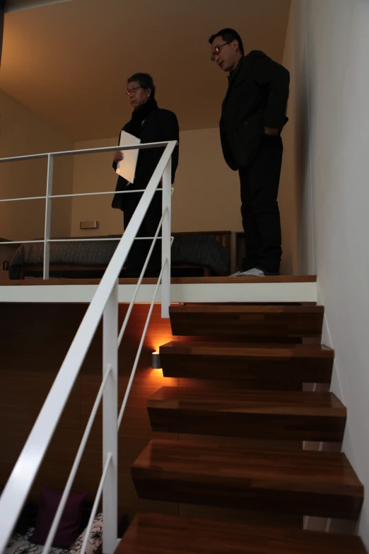 two men standing in a hallway, one of them holding a paper