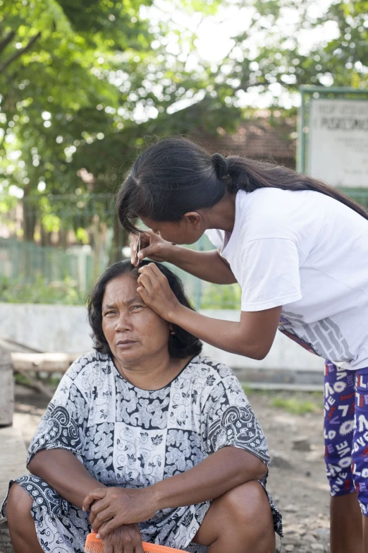 a woman is sitting with a child as another woman stands nearby