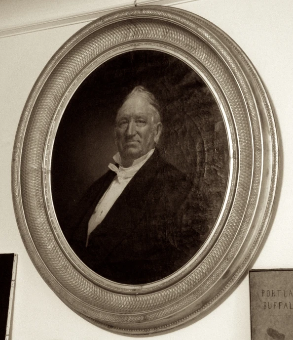 a man's portrait of a gentleman in a suit hangs on the wall