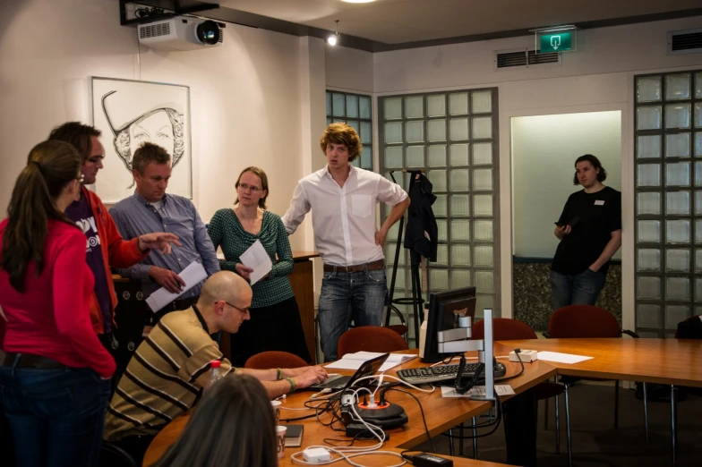 group of people gathered around table with computer equipment and microphones