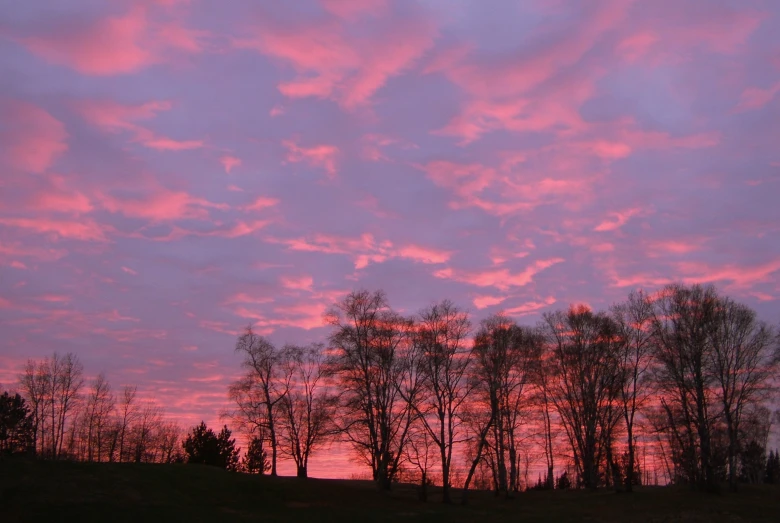 the bright pink sunset shines on a cloudy sky
