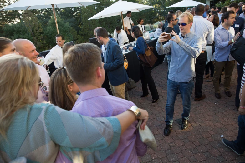 there is a group of people at an event and one man is taking a picture with his phone